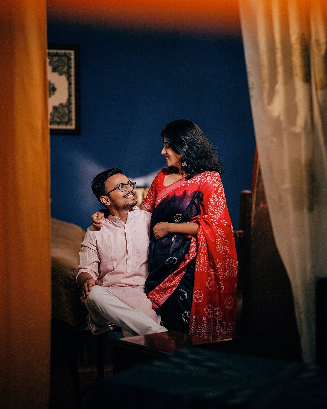 A couple sharing an intimate, smiling moment together indoors